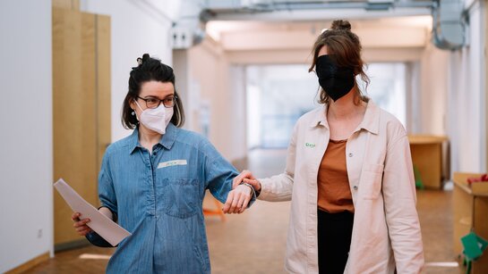 Zwei Personen, eine Person hat eine Augenmaske und wird von der anderern Person geführt