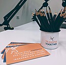 Auf dem Bild sieht man eine Tasse mit dem Logo des Projekts TRANSFER TOGETHER sowie Projektflyer im Podcaststudio.