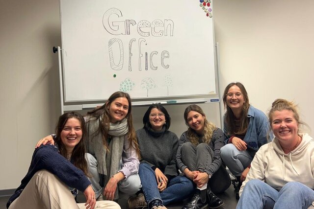 Die Mitglieder des Green Office der Pädagogischen Hochschule sitzen bei einem Meeting. Hinter ihnen an der Tafel steht Green Office. 