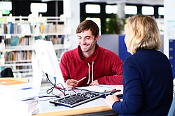 Studenten mit einer Frau an einem PC.