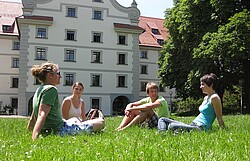 Das Foto zeigt sitzende Studierende auf einer Wiese des Weingartens.