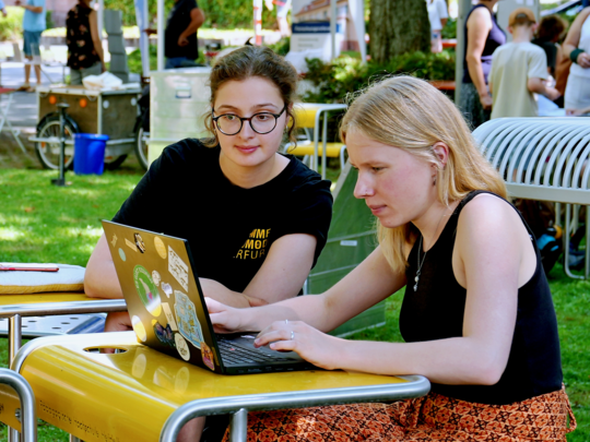 Zwei jungen Frauen sitzen vor einem Laptop.