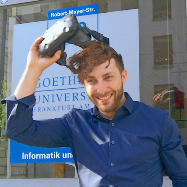 Prof. Dr. Andreas Dengel zieht sich eine VR-Brille vom Kopf, im Hintergrund ein Schild der Goethe-Universität Frankfurt.