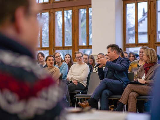 Das Bild zeigt Jürgen Dusel, der in der Aula der PH Heidelberg in einem Seminar der Bildungsfachkräfte sitzt. Um ihn herum sitzen Studierende. Herr Dusel spricht in ein Mikro. 