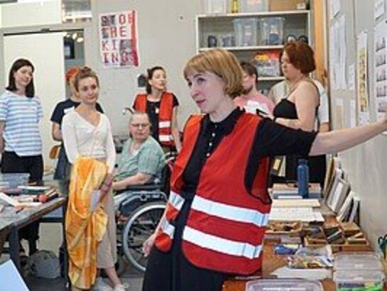 Das Bild zeigt verschiedene Menschen, die beim Seminar "Kunst und Inklusion" teilgenommen haben. Im Vordergrund steht eine Frau mit kürzerem blonden Haar, sie trägt eine rote Warnweste.