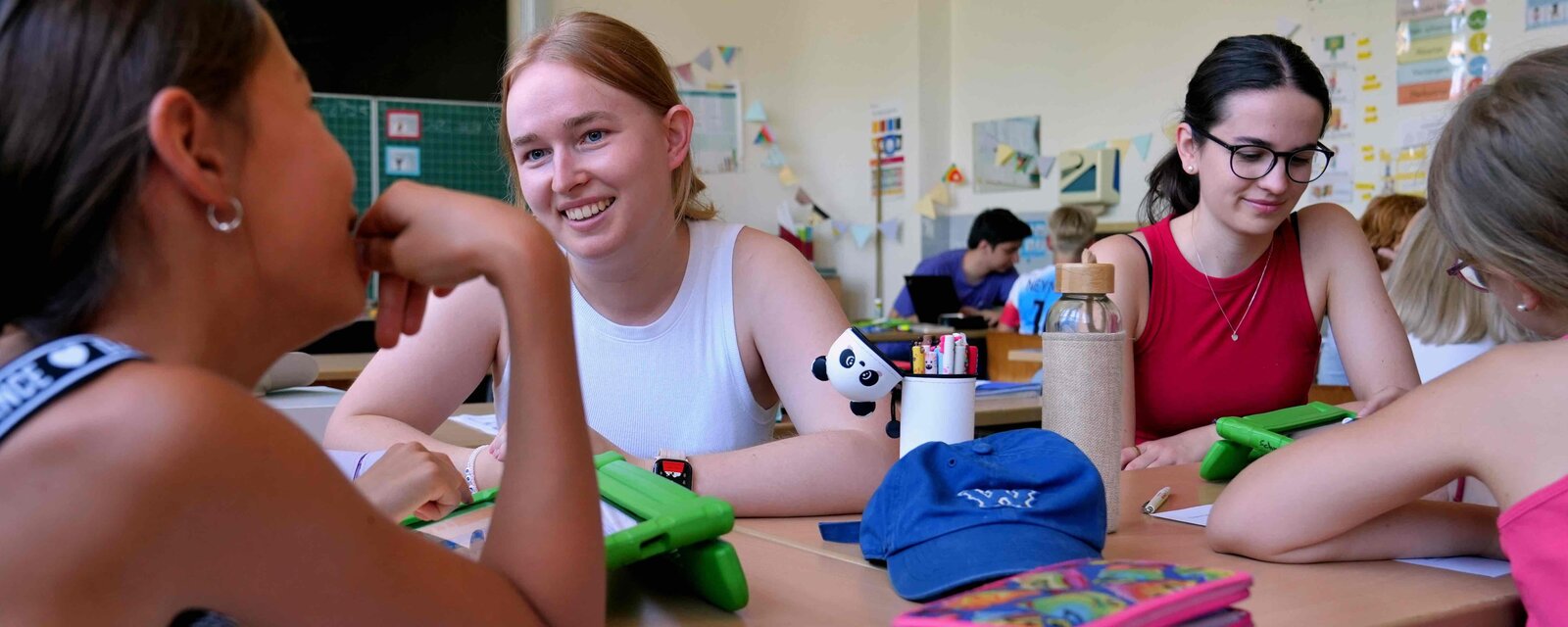 Studierende des Lehramt der Pädagogischen Hochschule Heidelberg arbeiten zusammen mit Kindern an Tablets.