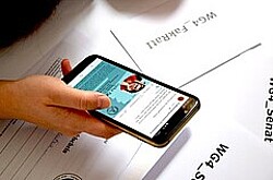 Hand, die ein Handy hält. Auf dem Handydisplay ist unscharf der Instagram-Account des StuPa zu sehen.