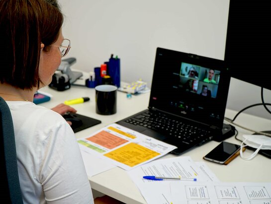 Das Bild zeigt eine Person vor einem Laptop sitzend.