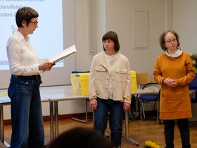 Das Bild zeigt Professorin Karin Vach, Rektorin der Pädagogischen Hochschule Heidelberg, die im Rahmen der Transitionsfeier den Qualifizierungsteilnehmerinnen Susann Bensch und Louisa Kabbe ihre Urkunden zur erfolgreich bestandenen Qualfizierung zur Bildungsfachkraft überreicht.