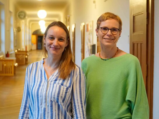 Das Bild zeigt Kathrin Ludwig und Stephanie Schleer im Flur des Altbaus der PH Heidelberg. 