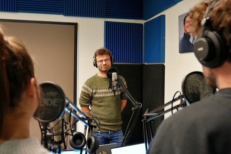 Zu sehen ist eine Unterhaltung von drei Personen in einem Podcast-Studio 