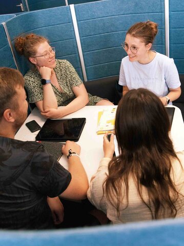 Vier Studierende besprechen sich an einem Tisch