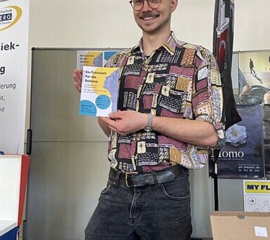 Student Gabriel präsentiert den Flyer für das Tutorium für die Stimme.