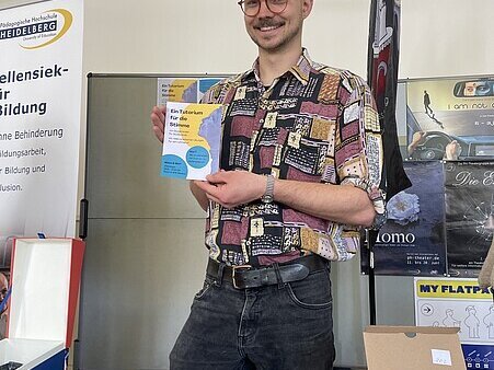 Student Gabriel präsentiert den Flyer für das Tutorium für die Stimme.