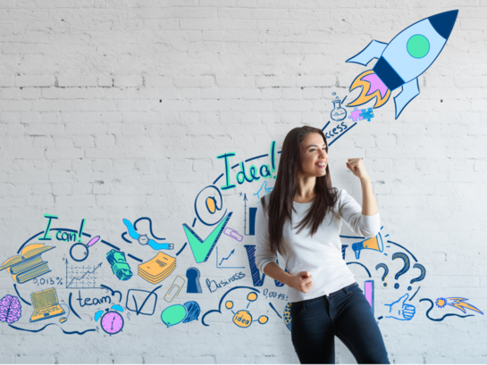 Eine junge Frau steht lächelnd in motivierter Pose vor einer Wand, auf der eine losfliegende Rakete abgebildet ist