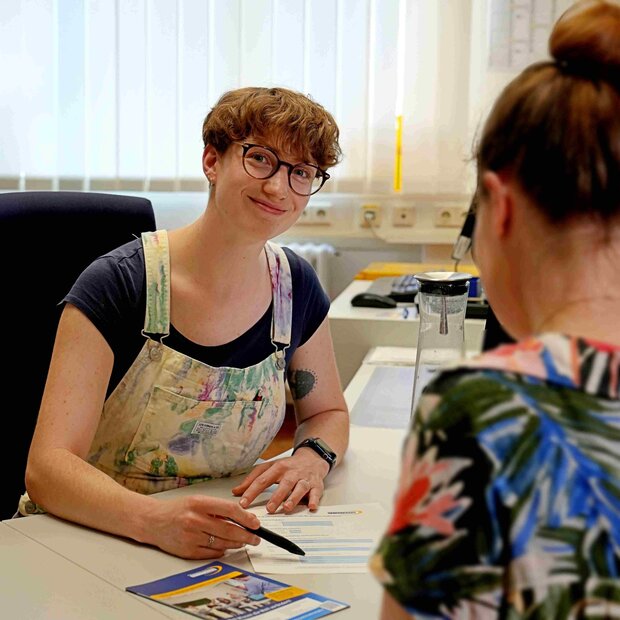 Mitarbeiterin des Studienbüros berät am Schreibtisch eine Studentin