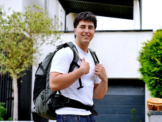 Das Foto zeigt einen Studenten mit einem Rucksack auf dem Rücken.