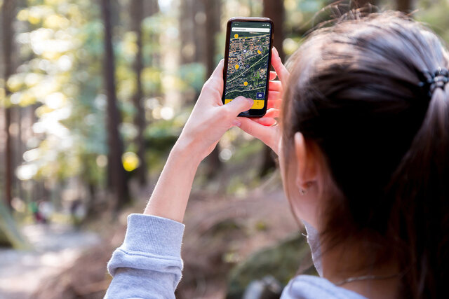 Person mit Handy und App im Wald