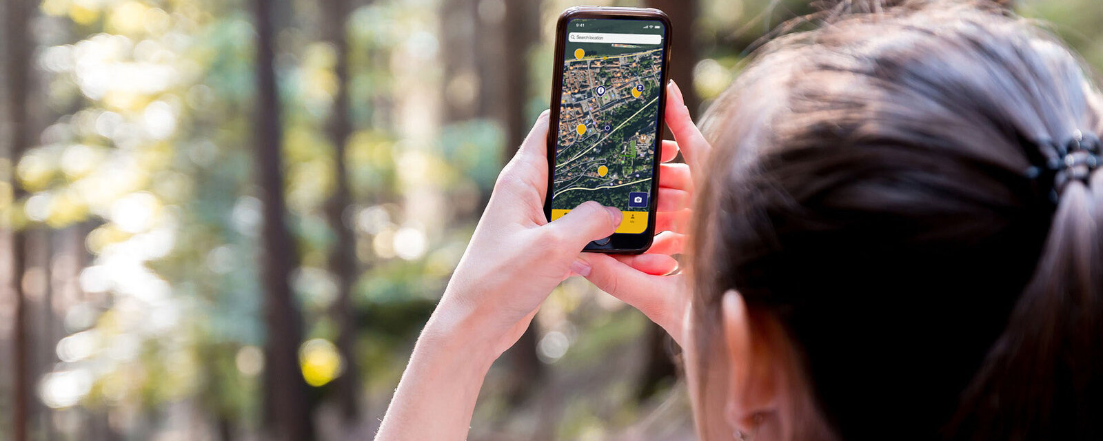 Person mit Handy und App im Wald