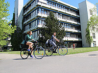 fahrradfahrende Mitarbeitende vor der Pädagogischen Hochschule