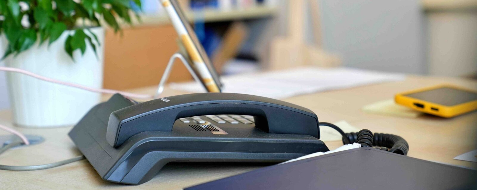 Ein Telefon auf einem Schreibtisch der Haushalt und Finanzen, im Hintergrund ein Bücherregal im Altbau der Pädagogischen Hochschule Heidelberg. 