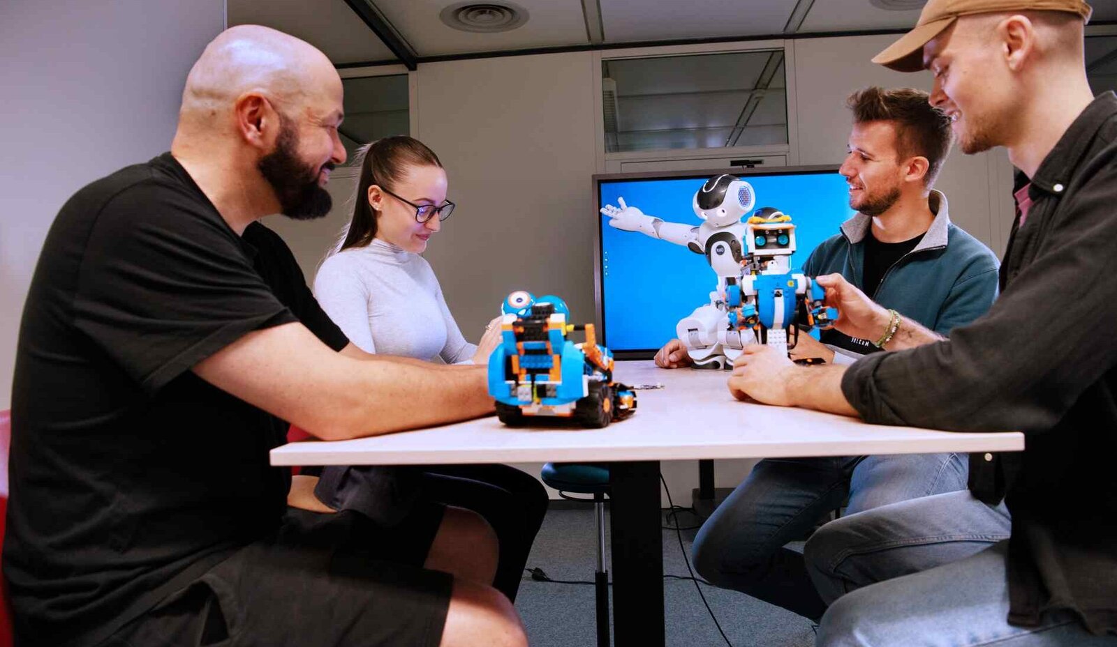 Vier Student*innen und der Nao Roboter unterhalten sich über ein Projekt.