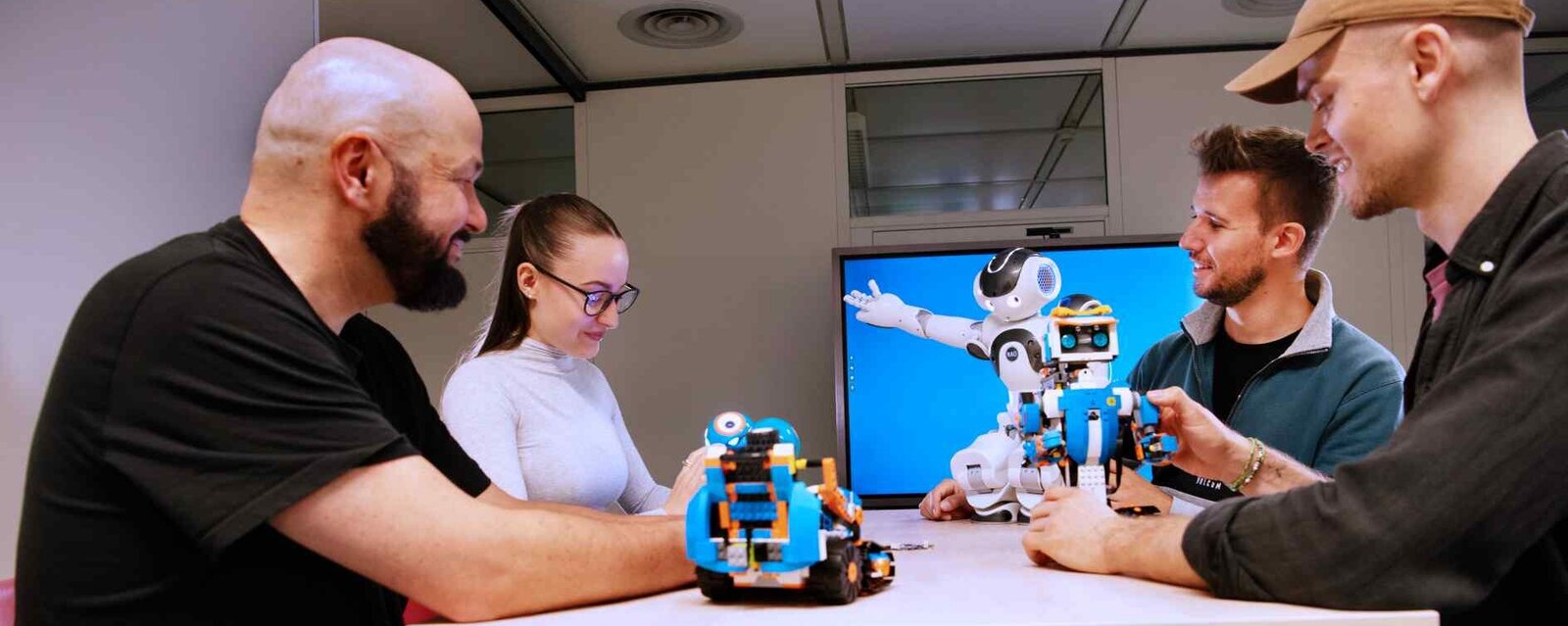 Vier Student*innen und der Nao Roboter unterhalten sich über ein Projekt.