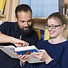 Auf dem Symbolbild sind ein junger Mann und eine junge Frau zu sehen. Sie hält ein Buch und er zeigt ihr darin etwas. Copyright: PH Heidelberg