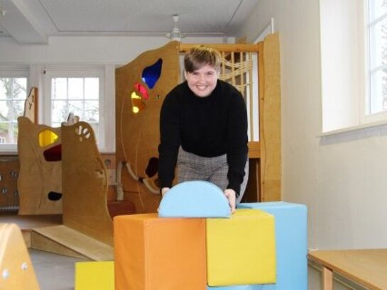 Das Foto zeigt eine junge Frau in einem Raum mit vielen Spielgeräten.