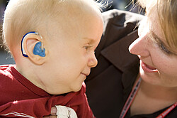 Mutter die ihr Kind mit CHARGE Syndrom anlächelt.