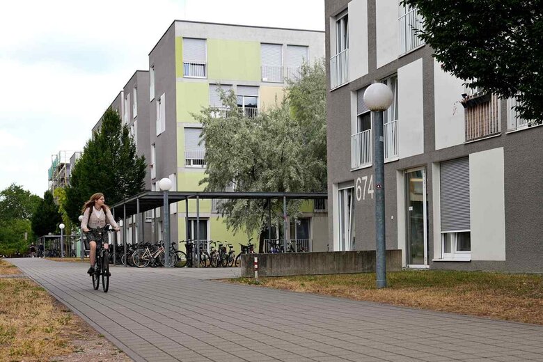 Zu sehen sind Wohnheime und eine Studentin auf einem Fahrrad.
