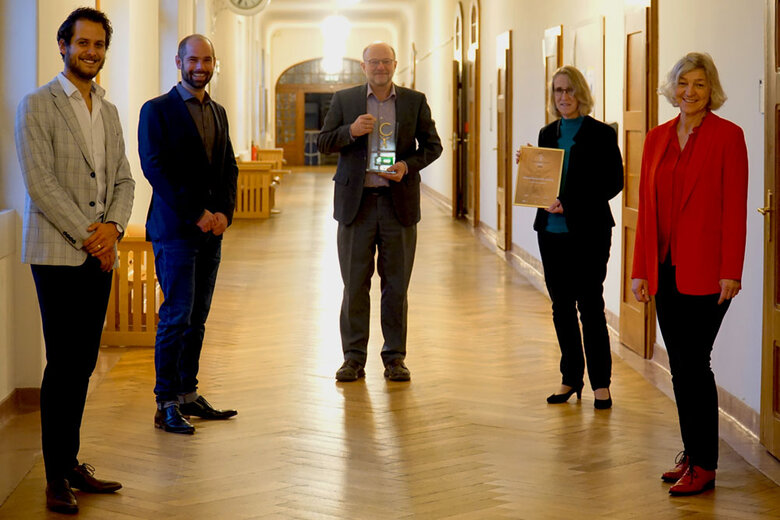 Das Bild zeigt Steffen Klink, Sebastian Stumpf, Hans-Werner Huneke, Stephanie Wiese-Heß und Petra Dann. Sie stehen im Altbauflur der Hochschule. Herr Huneke und Frau Wiese-Heß halten jeweils die Auszeichnung in der Hand.