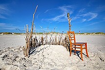 Strandburg und ein Stuhl davor an einem Sandstrand. Copyright Pixabay