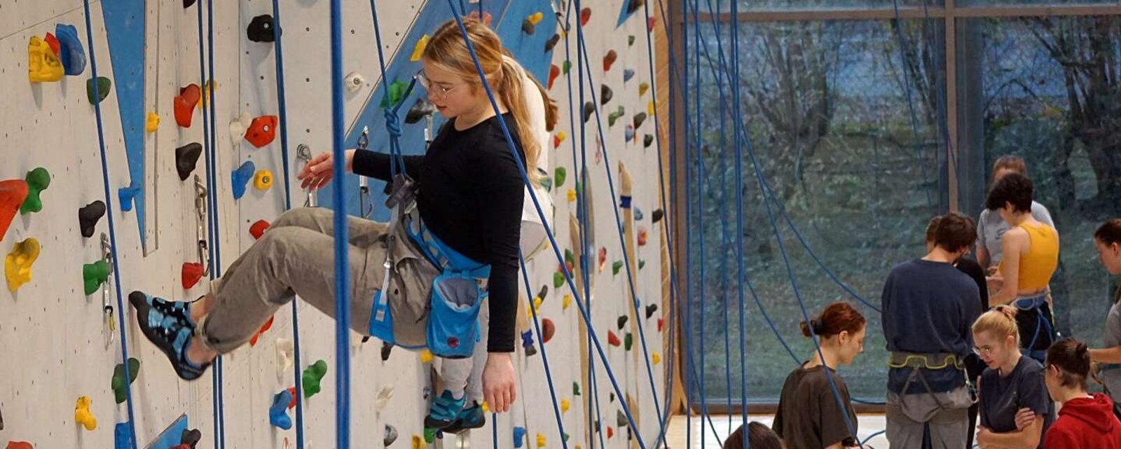 Studierende der Sportpädagogik und Sportwissenschaften sind in der Kletterhalle der Pädagogischen Hochschule Heidelberg und seilen sich gerade ab.