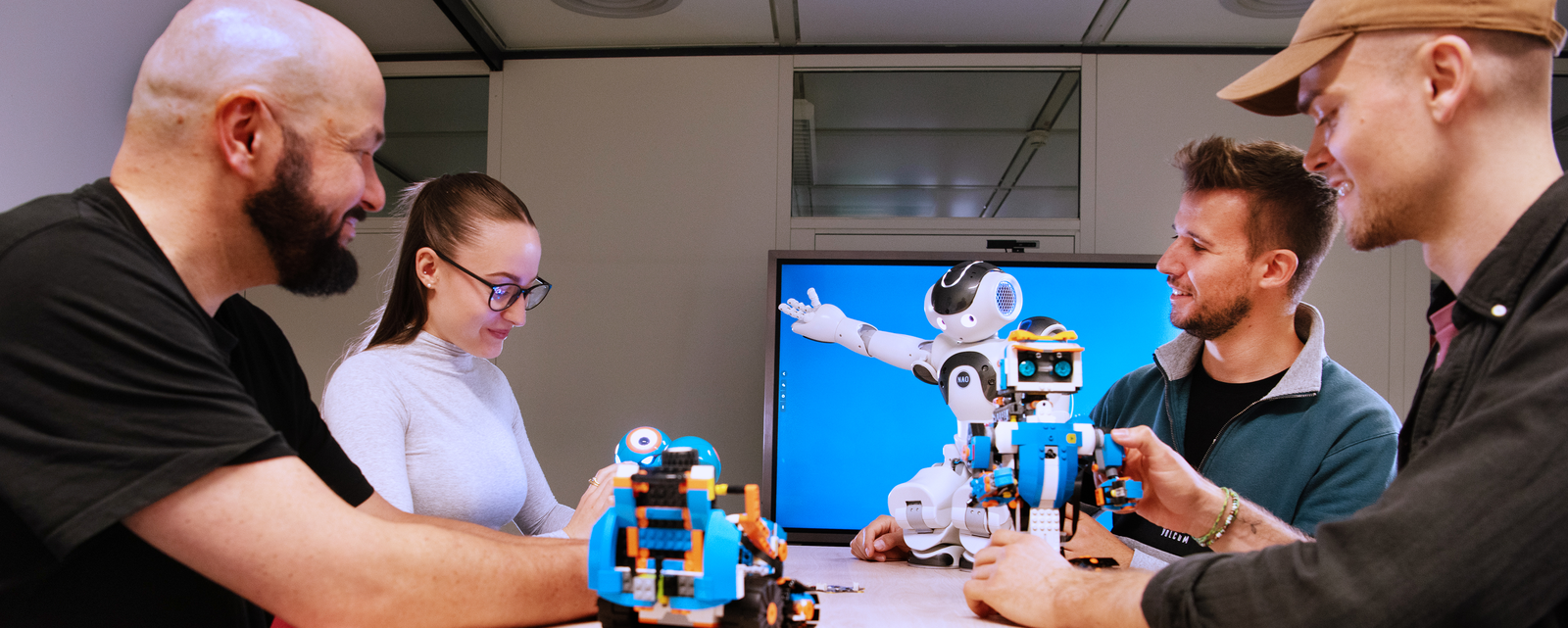 Vier Student*innen und der Nao Roboter unterhalten sich über ein Projekt.