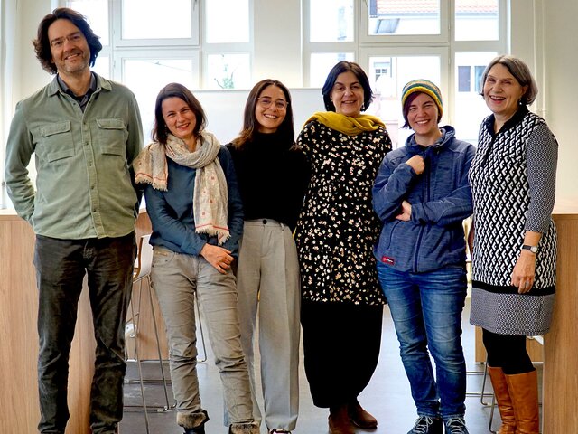 Sechs Wissenschaftler:innen des Projekts stehen in einer Reihe und schauen freundlich in die Kamera