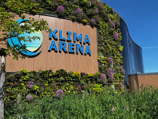 Grün bewachsene Außenansicht der KLIMA ARENA