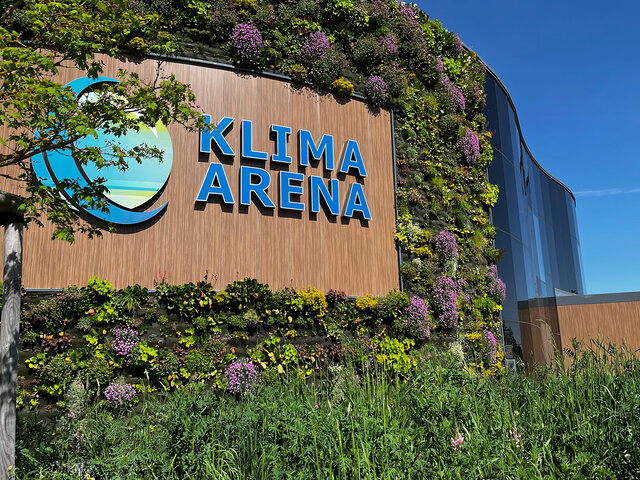 Grün bewachsene Außenansicht der KLIMA ARENA