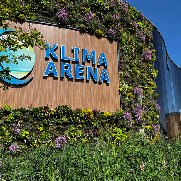 Grün bewachsene Außenansicht der KLIMA ARENA