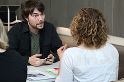 Mann und eine Frau die sich gegenüber sitzen und sich unterhalten.