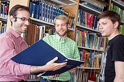 drei Männer in einer Bibliothek. 