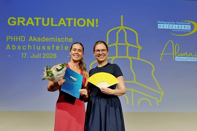 Zu sehen sind eine Absolvent:in und Prorektorin Prof. Dr.in Marita Friesen auf der Bühne.