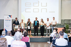 Auf dem Bild sieht man die Sieger-Teams auf der Bühne. Vorne sieht man das Publikum von hinten. Das Bild wurde in der Festhalle der Hochschule aufgenommen.