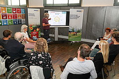 Das Archivbild zeigt Menschen im Stuhlkreis, die auf ein Whiteboard schauen. Das Foto wurde während einer Tagung an der Hochschule aufgenommen. 