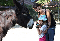 Das Foto zeigt eine Frau und ein Kind mit einem Esel.