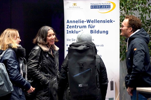 Das Bild zeigt Menchen, die sich unterhalten. Im Hintergund ist ein Roll-up des AW-ZIB.
