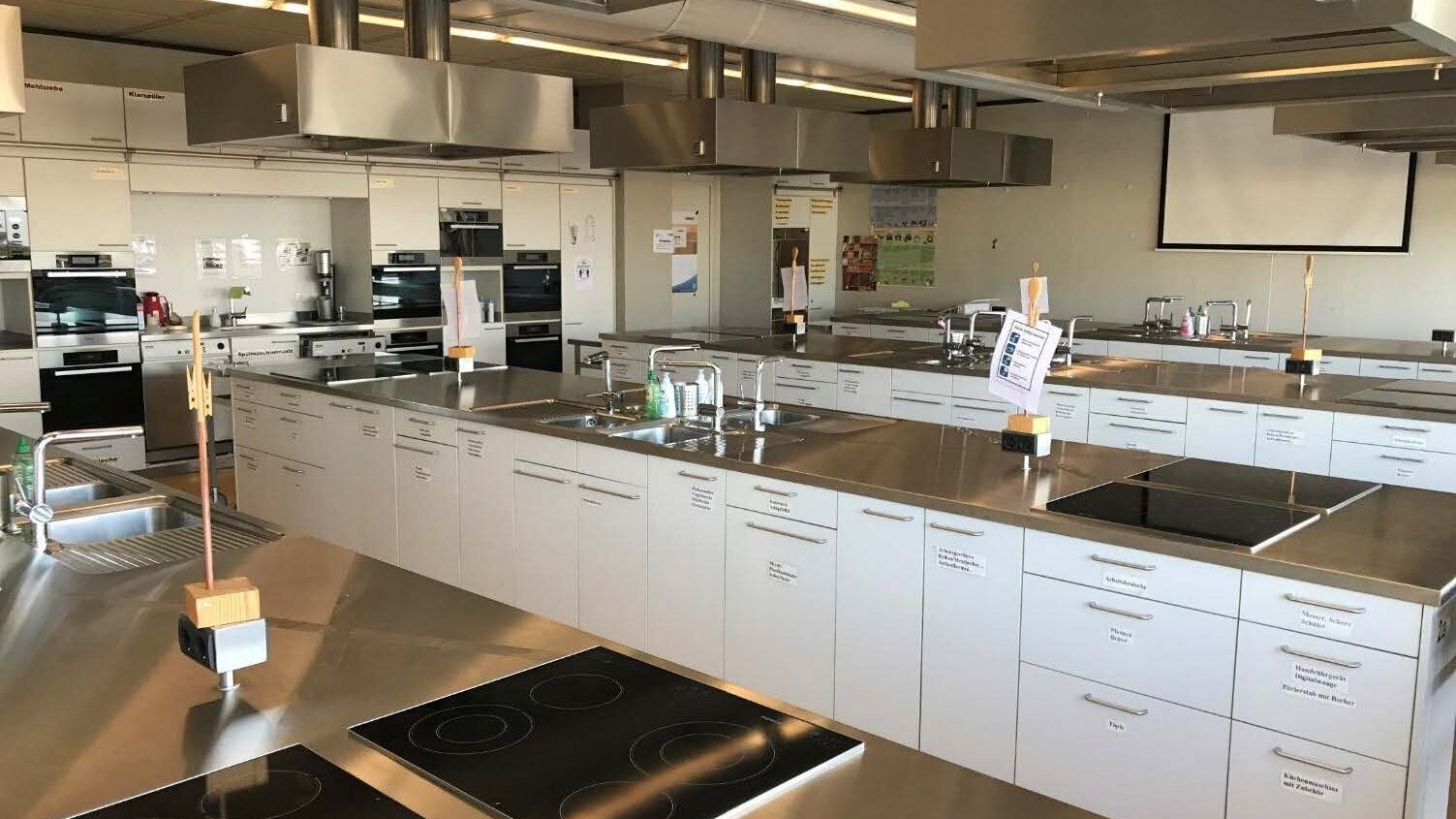 Blick in die Lehrküche des Fachs Alltagskultur und Gesundheit: Zu sehen sind viele Küchenzeilen in einem großen Raum
