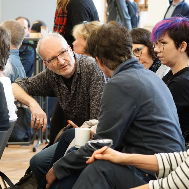 Blick ins Publikum während des hochschulweiten Workshops. Die Menschen unterhalten sich.