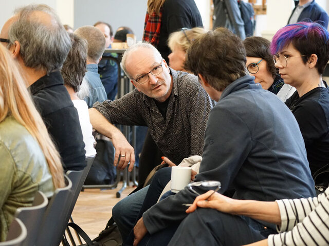 Blick ins Publikum während des hochschulweiten Workshops. Die Menschen unterhalten sich.