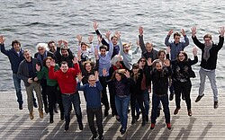 Gruppenbild von Menschen die ihre Arme in die Luft strecken von der Doktorierendentagung auf dem Campus Luzern. 